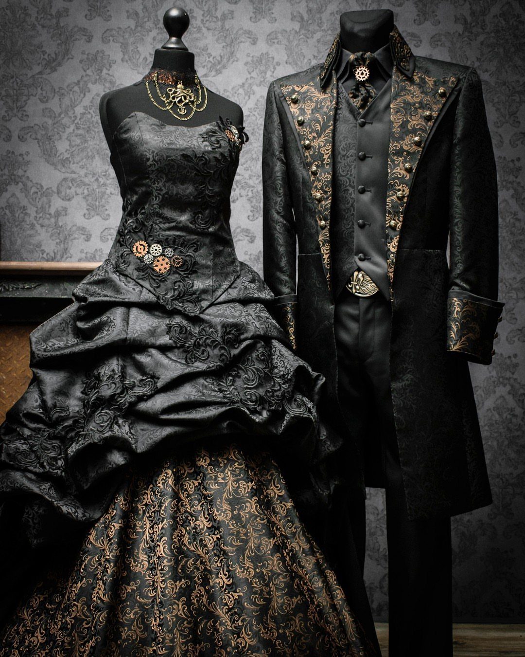 Victorian gothic wedding gown and groom's tailcoat in black and gold on mannequins.