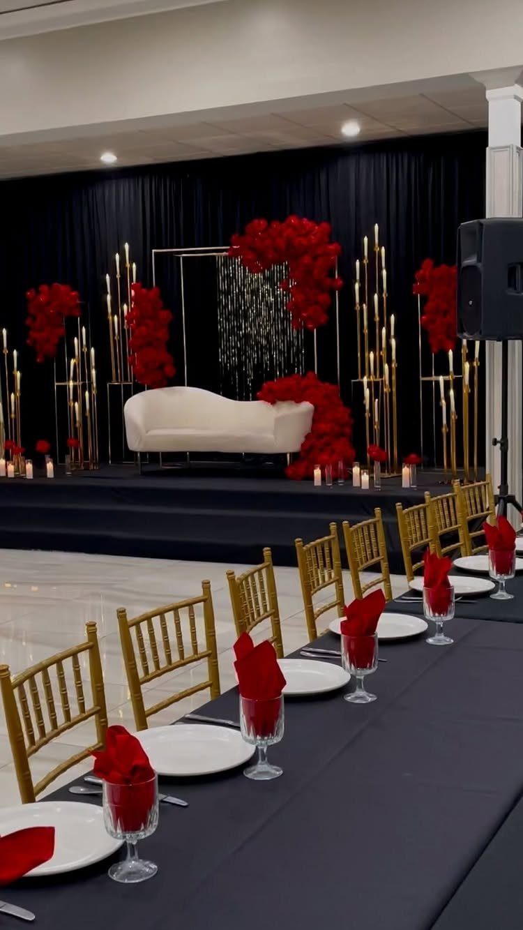 Black dining table with white plates and red napkins in a gothic setting.