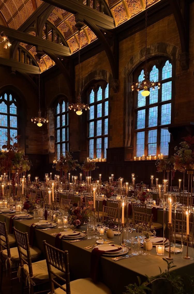 Grand hall with stone walls, iron chandeliers, and candlelit dining tables for a wedding.