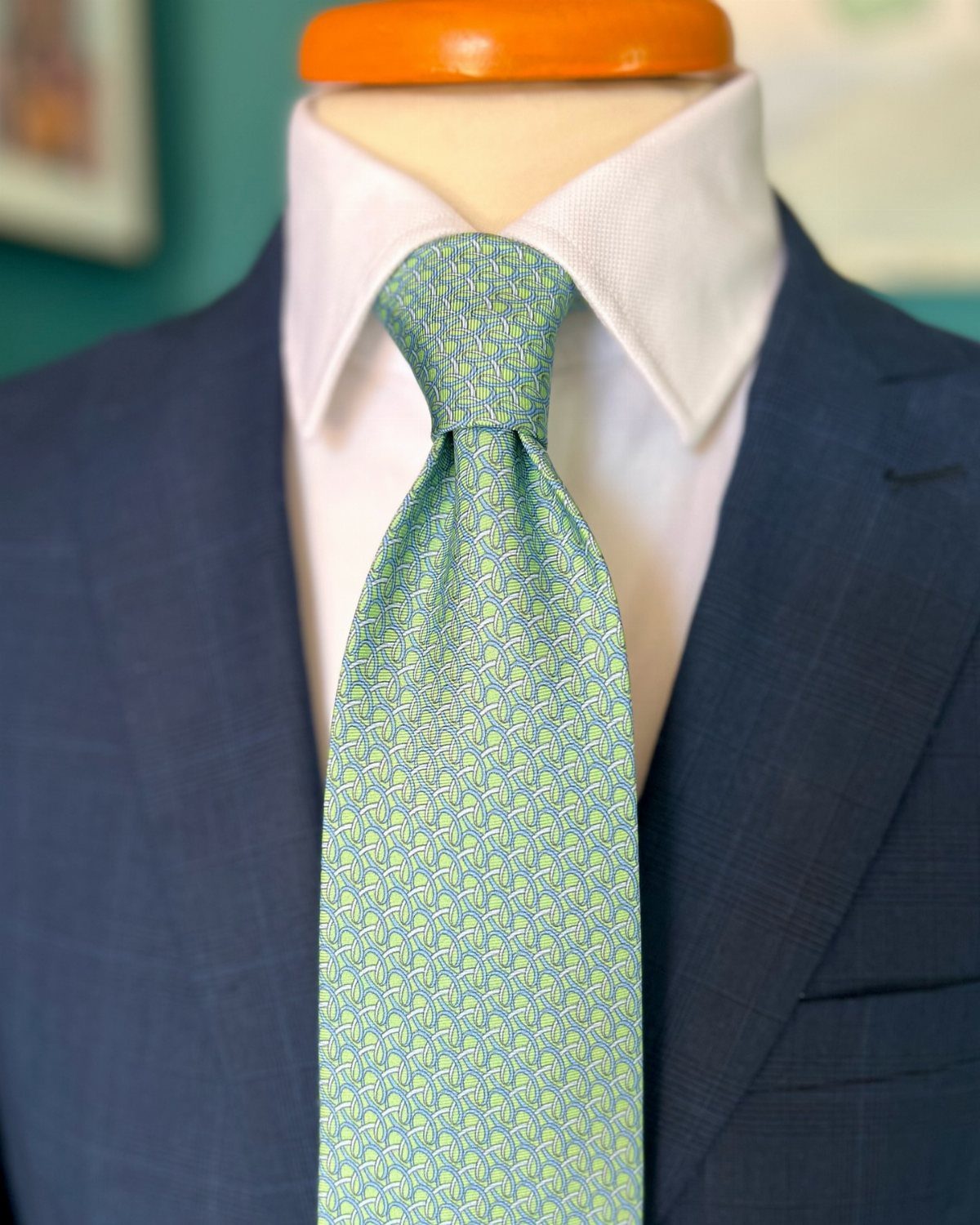 Light green patterned necktie paired with a white shirt and dark blue suit jacket.