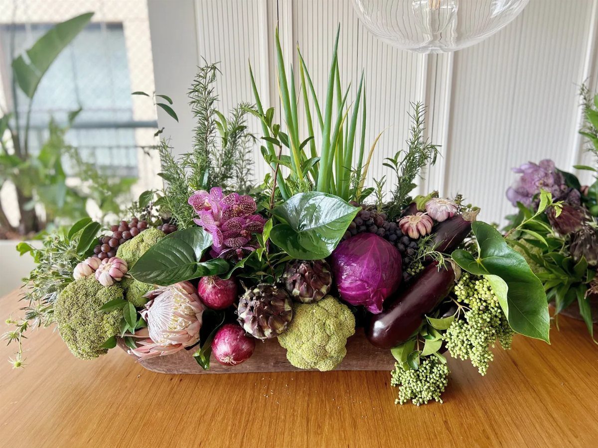 Purple cabbage and green vegetables arranged in a rustic wooden trough centerpiece.