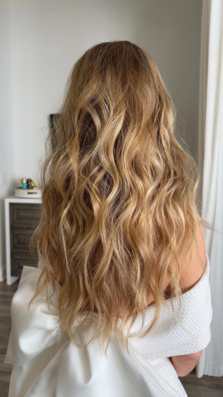 6 Hair Down Wedding Styles That Keep the Veil, the Volume, and the Vibe 3 Long blonde hair styled in loose, textured beachy waves worn with a white dress.