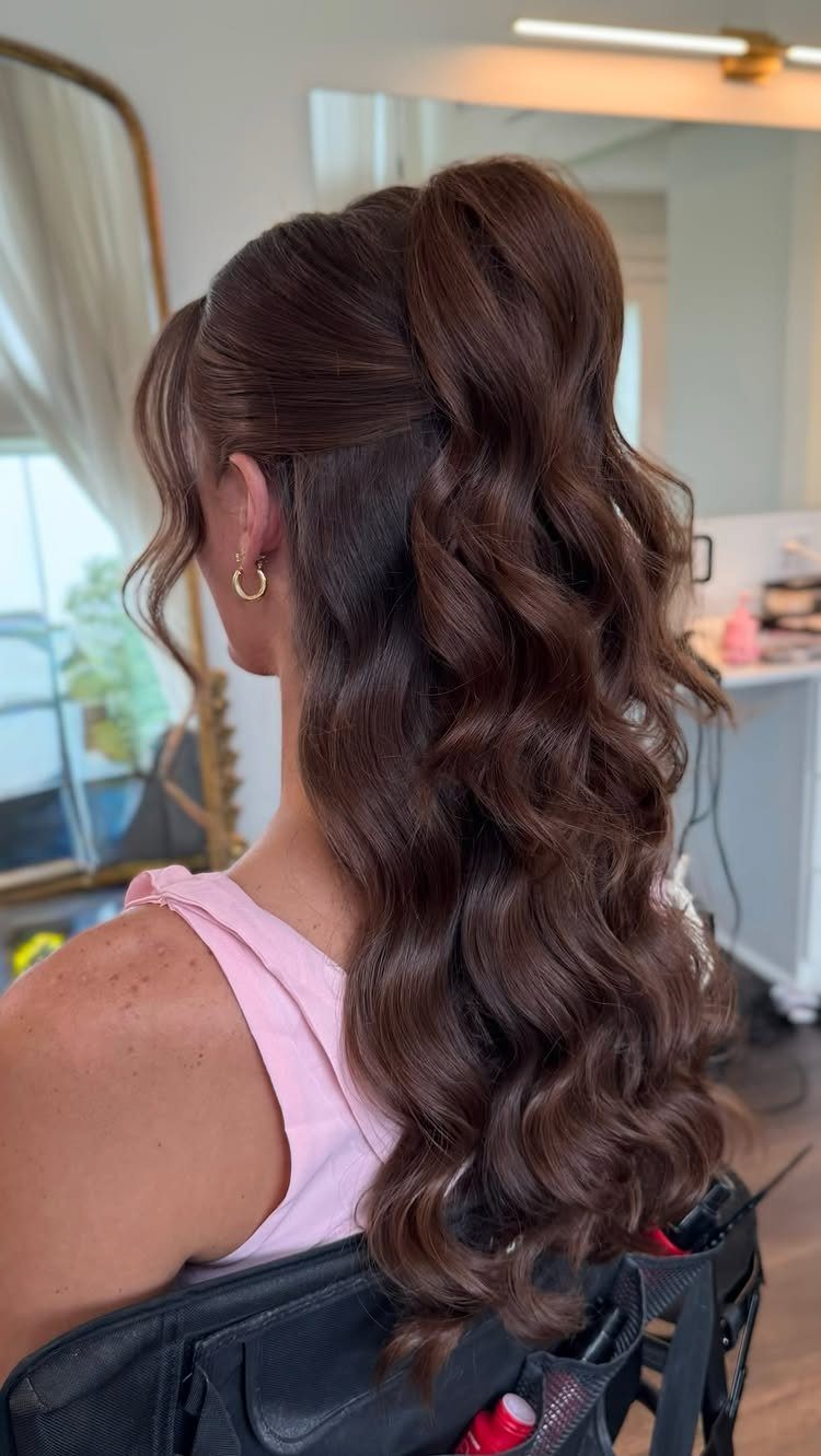 6 Hair Down Wedding Styles That Keep the Veil, the Volume, and the Vibe 2 Woman with long brown hair styled in a voluminous half-up, half-down wavy hairstyle.