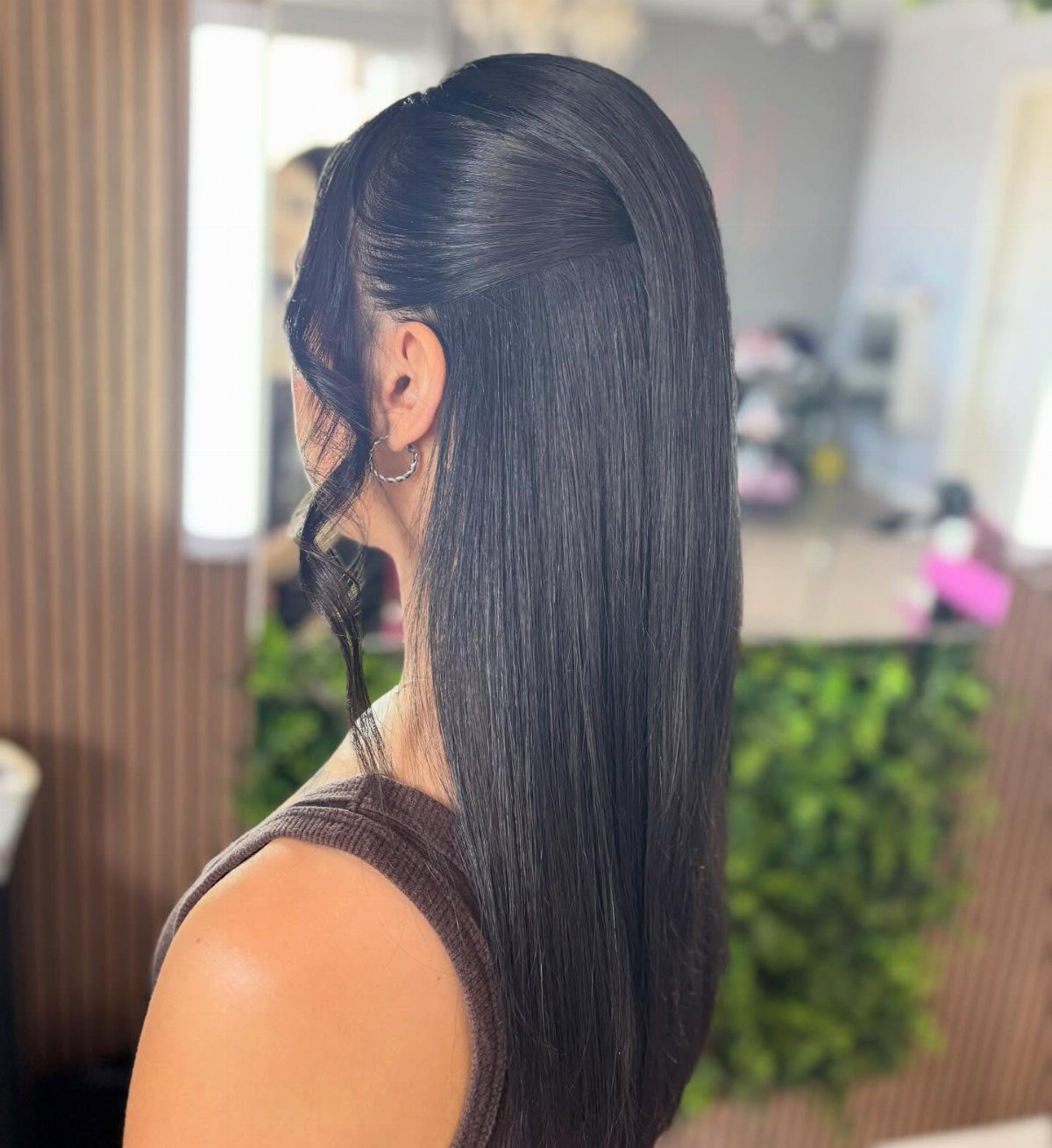 6 Hair Down Wedding Styles That Keep the Veil, the Volume, and the Vibe 4 A woman with long, dark, sleek, and straight hair styled smoothly behind her ear.