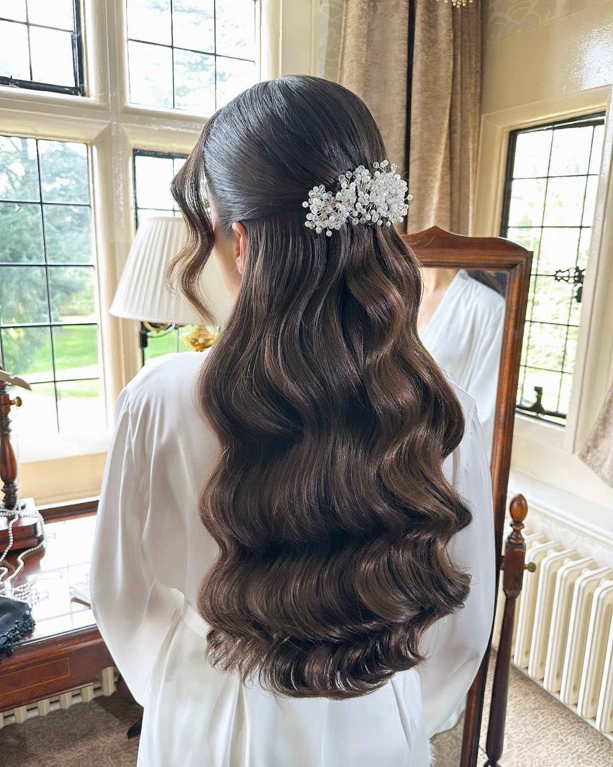 6 Hair Down Wedding Styles That Keep the Veil, the Volume, and the Vibe 5 Woman with long dark hair styled in voluminous, structured vintage waves with a floral hairpiece.