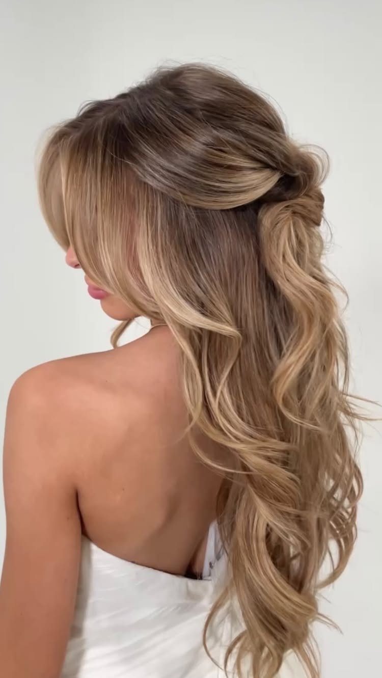 18 Hoco Updo Hairstyles From Braids to Sleek Buns 15 Long blonde wavy hair styled in a half-up, half-down hairstyle on a woman.