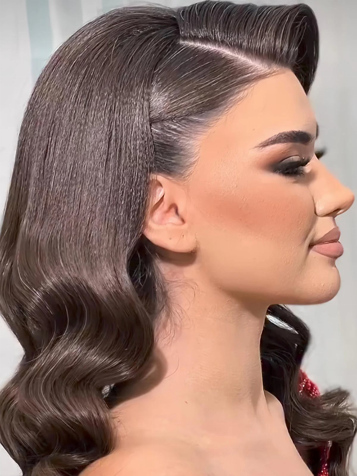 18 Hoco Updo Hairstyles From Braids to Sleek Buns 8 Woman with dark hair styled in deep, structured side-swept glamorous waves and a vintage roll.
