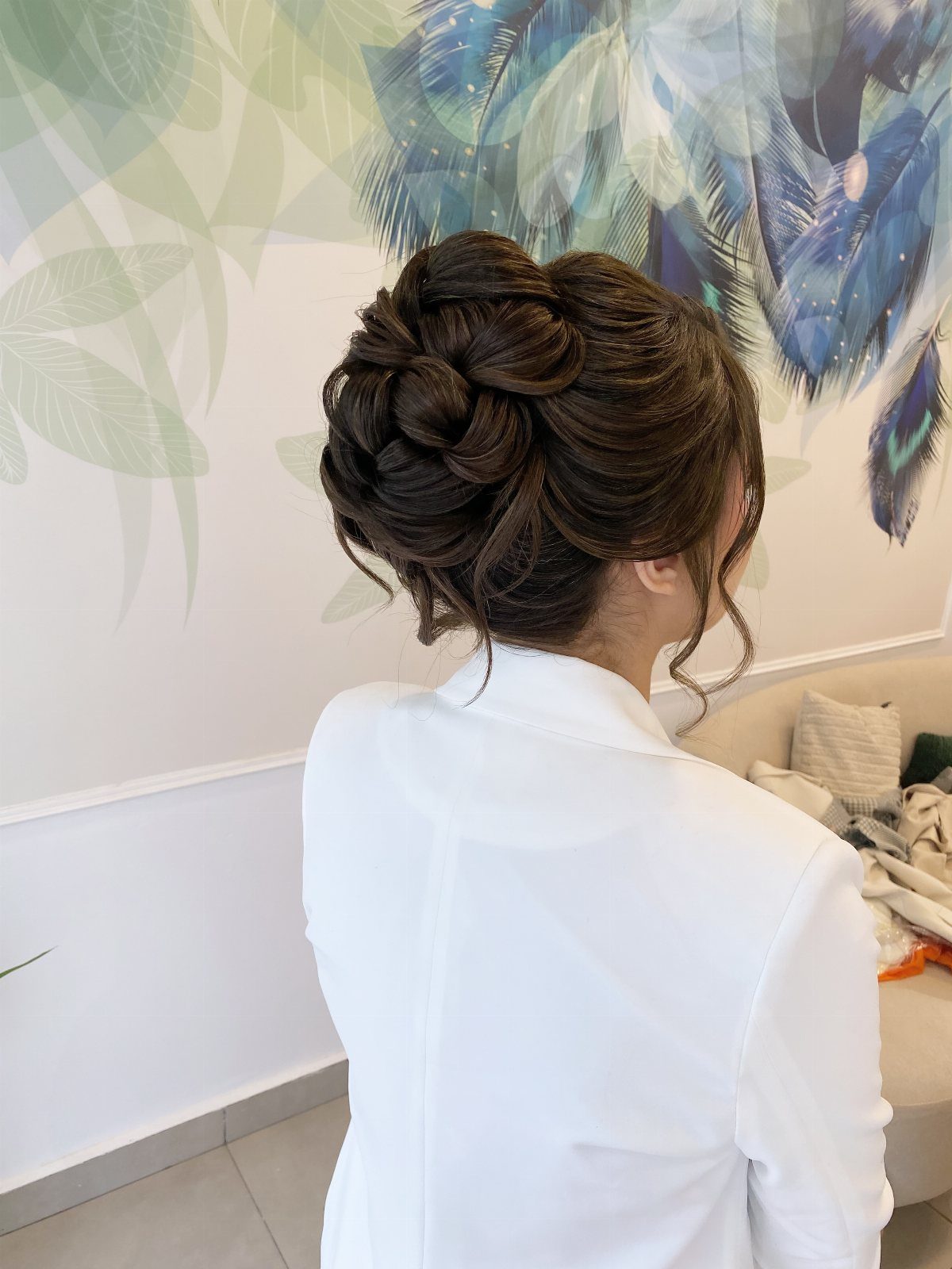 18 Hoco Updo Hairstyles From Braids to Sleek Buns 13 A woman with an intricate, voluminous dark brown twisted updo hairstyle and white shirt.