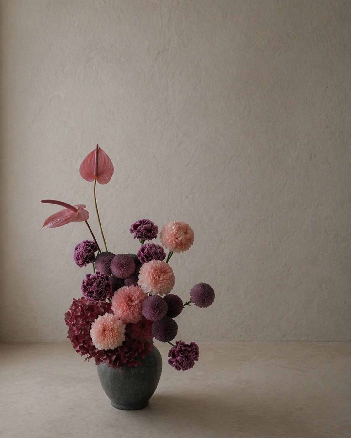 15 Ideas de Ramos de Flores for Every Table and Season 9 Asymmetrical floral arrangement with purple and pink flowers in a dark grey vase.