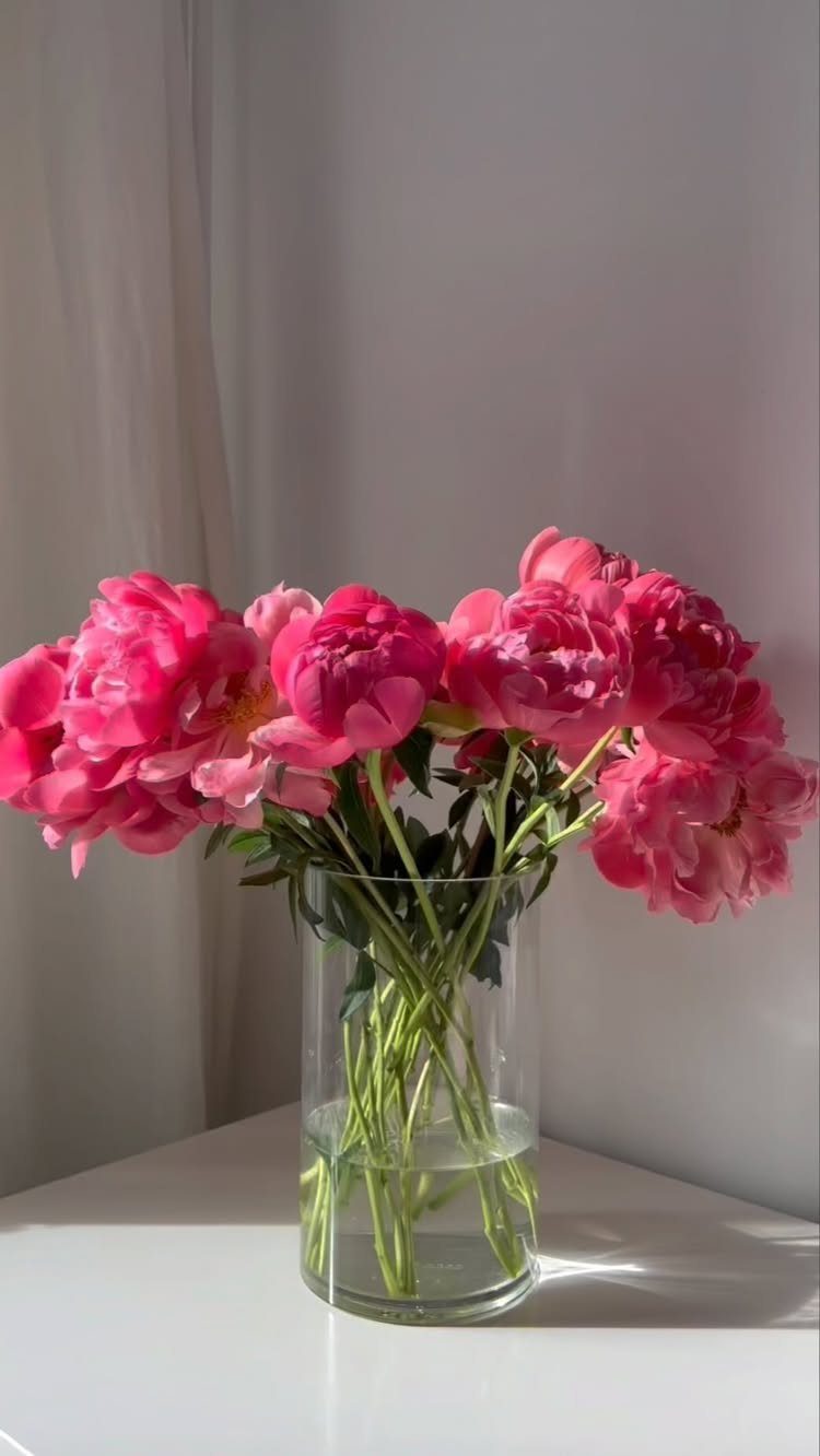 15 Ideas de Ramos de Flores for Every Table and Season 6 Bright pink peonies in a clear glass vase on a white table.