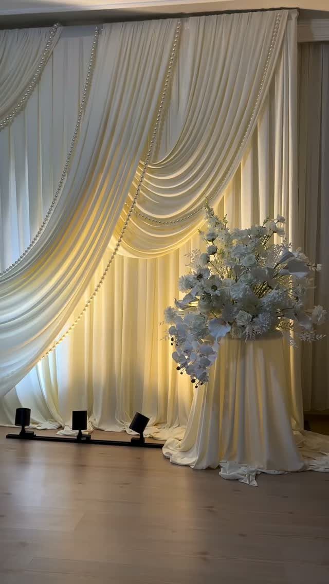 Round table with ivory floor-length tablecloth and large white floral centerpiece
