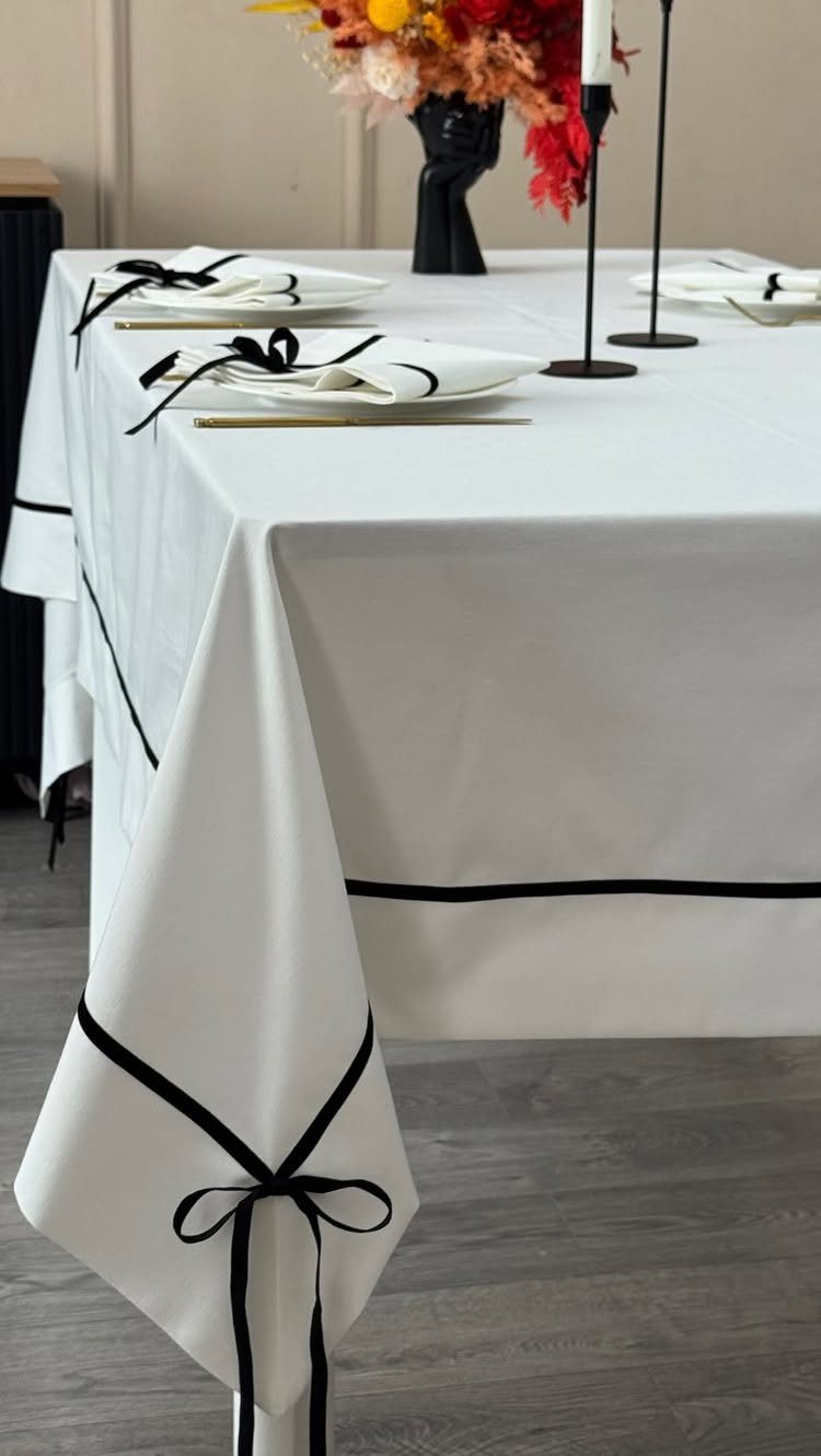 Ivory tablecloth with black ribbon trim and bows on a set table
