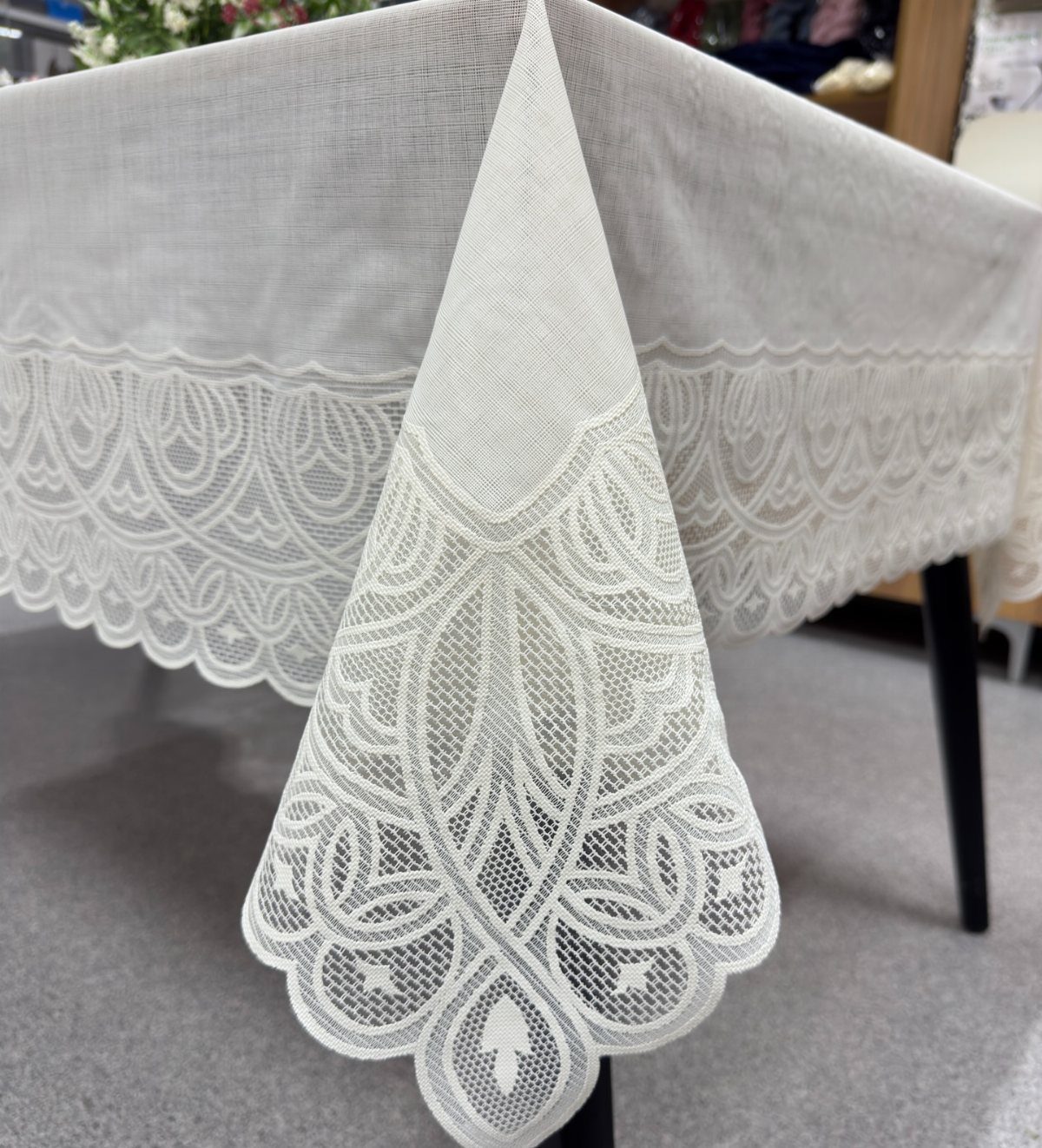 Ivory tablecloth with a detailed lace border and scalloped edges on a table.