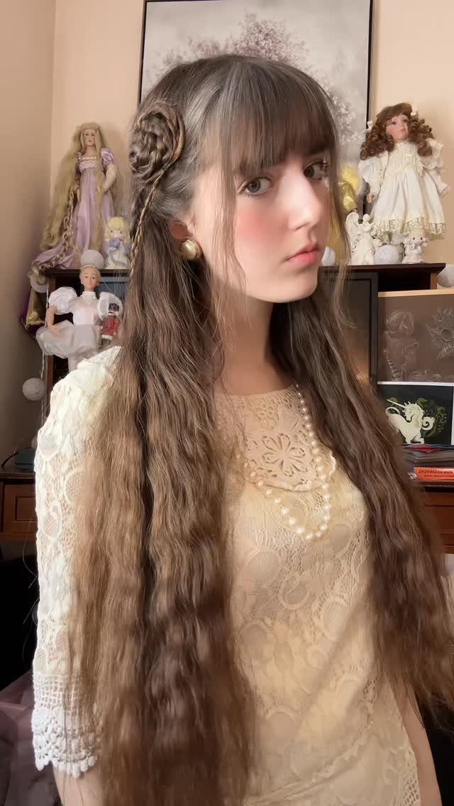 16 Long Hair Half Up Half Down Hairstyles for Real Life 8 Young woman with long wavy hair featuring a braided rose hairstyle on the side.
