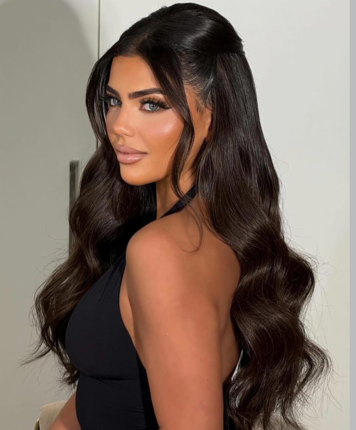 16 Long Hair Half Up Half Down Hairstyles for Real Life 7 Woman with long dark wavy hair in a half-up, half-down hairstyle posing in a black top.