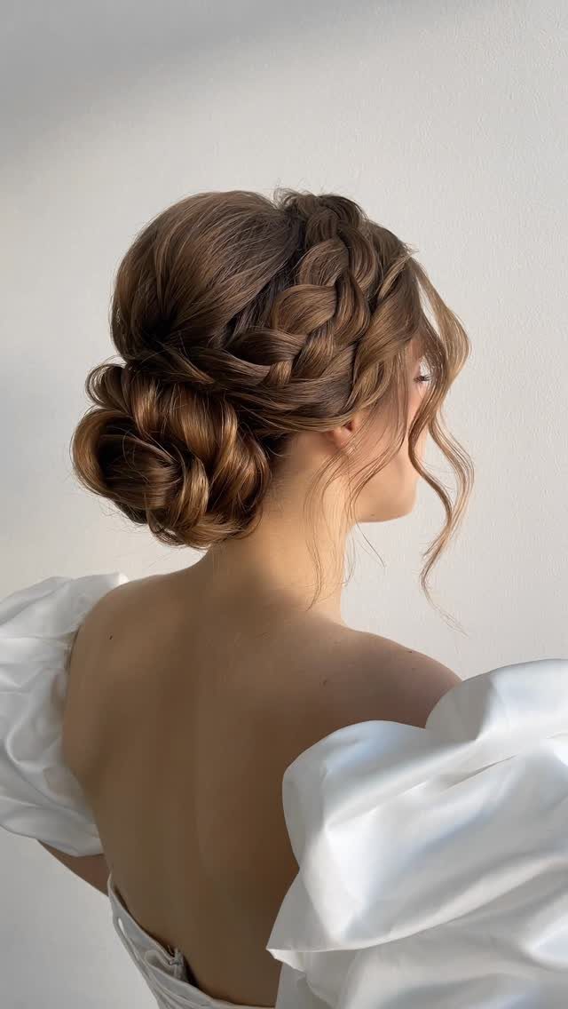 18 Low Messy Bun for Wedding Ideas with Braids and Florals 14 Woman with a low messy bun and side braid wearing a white wedding dress.