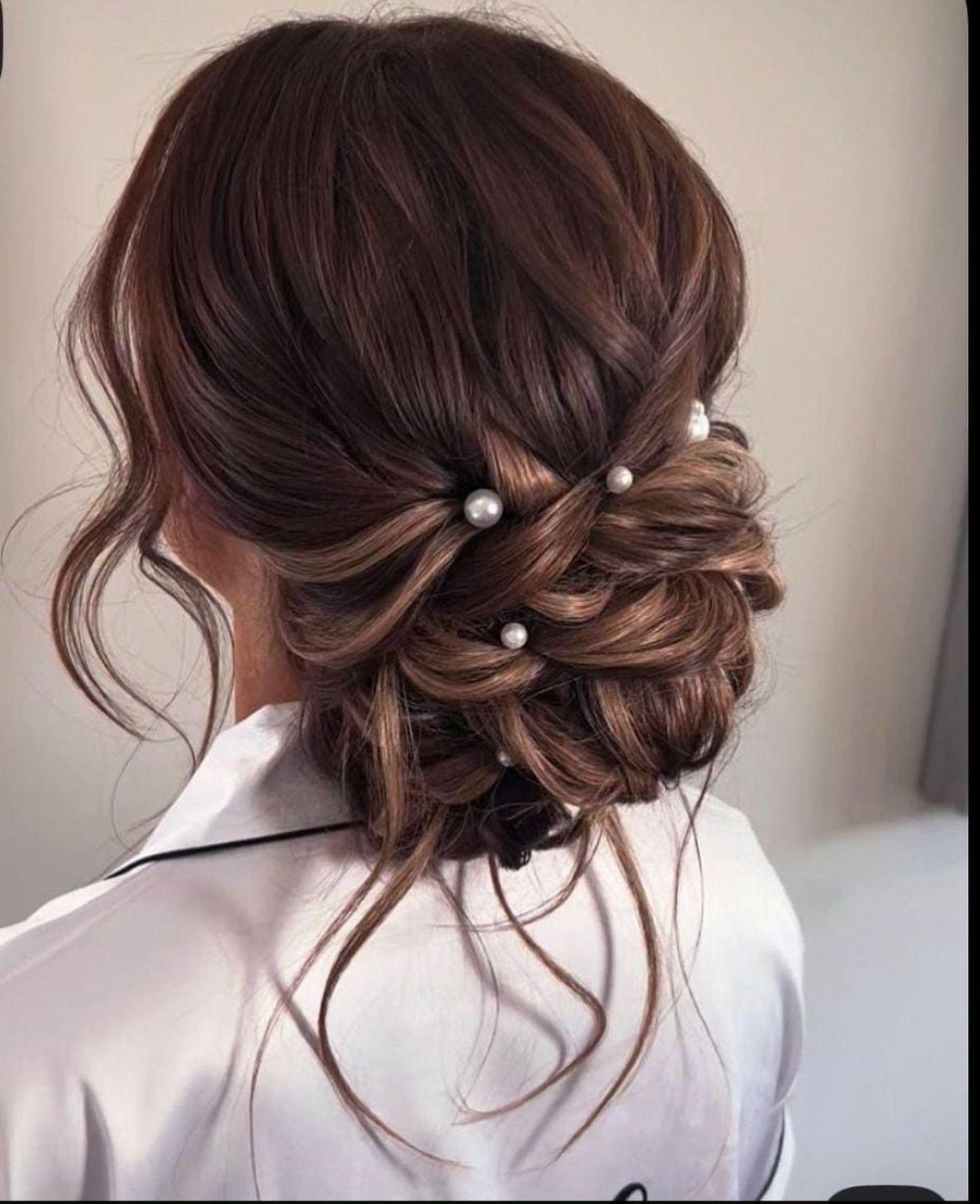 18 Low Messy Bun for Wedding Ideas with Braids and Florals 6 Brown hair styled in a low messy bun embellished with white pearl pins.