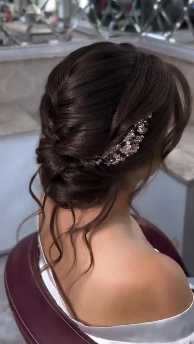 18 Low Messy Bun for Wedding Ideas with Braids and Florals 16 Low messy bun with a sparkling floral hairpiece on dark brown hair.