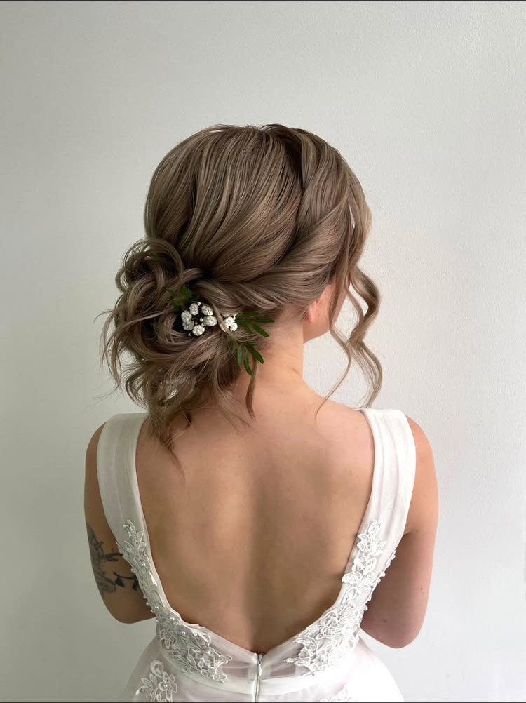 18 Low Messy Bun for Wedding Ideas with Braids and Florals 13 Low messy bun with white flowers on a woman wearing a white wedding dress