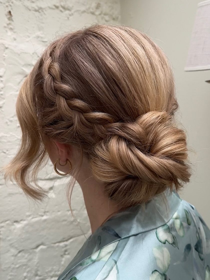 18 Low Messy Bun for Wedding Ideas with Braids and Florals 5 Blonde hair styled in a low bun with a side French lace braid.