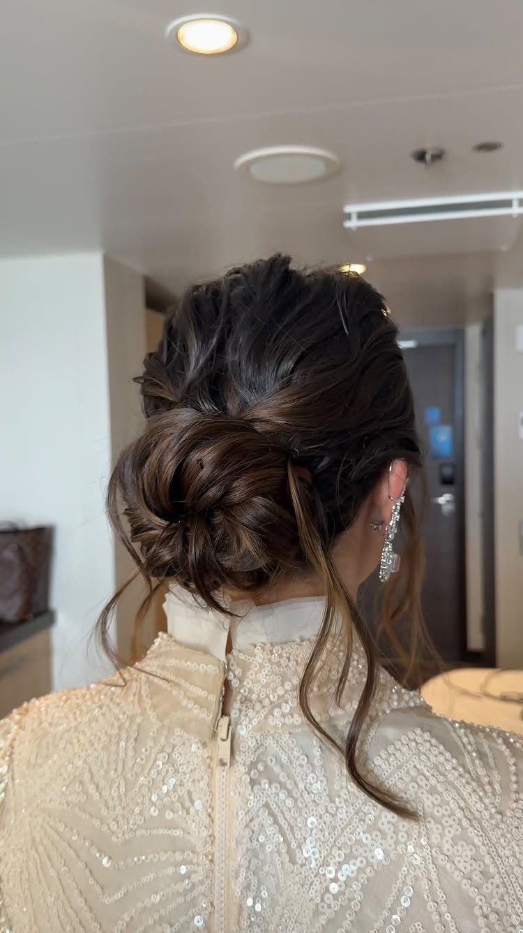 18 Low Messy Bun for Wedding Ideas with Braids and Florals 2 Brown hair styled in a textured low messy bun with loose face-framing strands.
