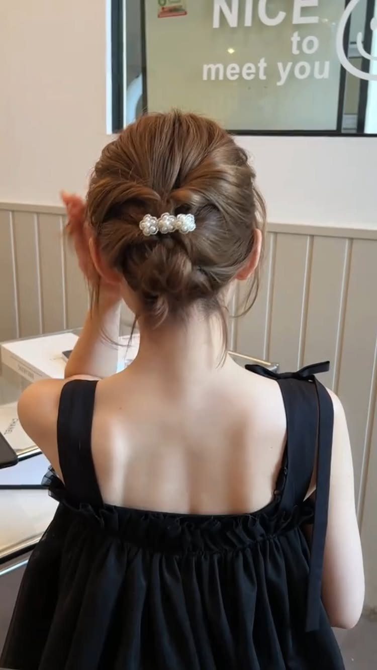 18 Low Messy Bun for Wedding Ideas with Braids and Florals 9 Low messy bun with pearl hair clip on brown hair, back view.