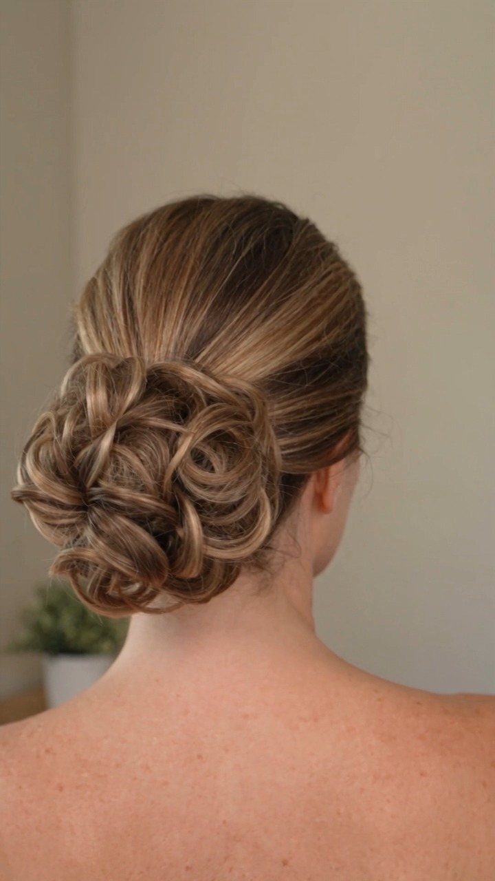 18 Low Messy Bun for Wedding Ideas with Braids and Florals 11 Woman's light brown hair styled in a voluminous, textured low messy bun.