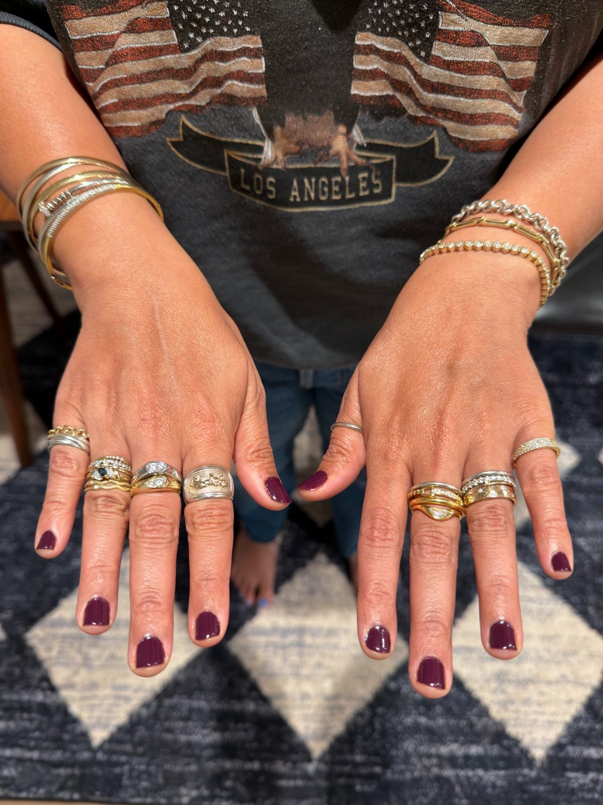Hands and arms adorned with multiple gold and silver rings and beaded bracelets.