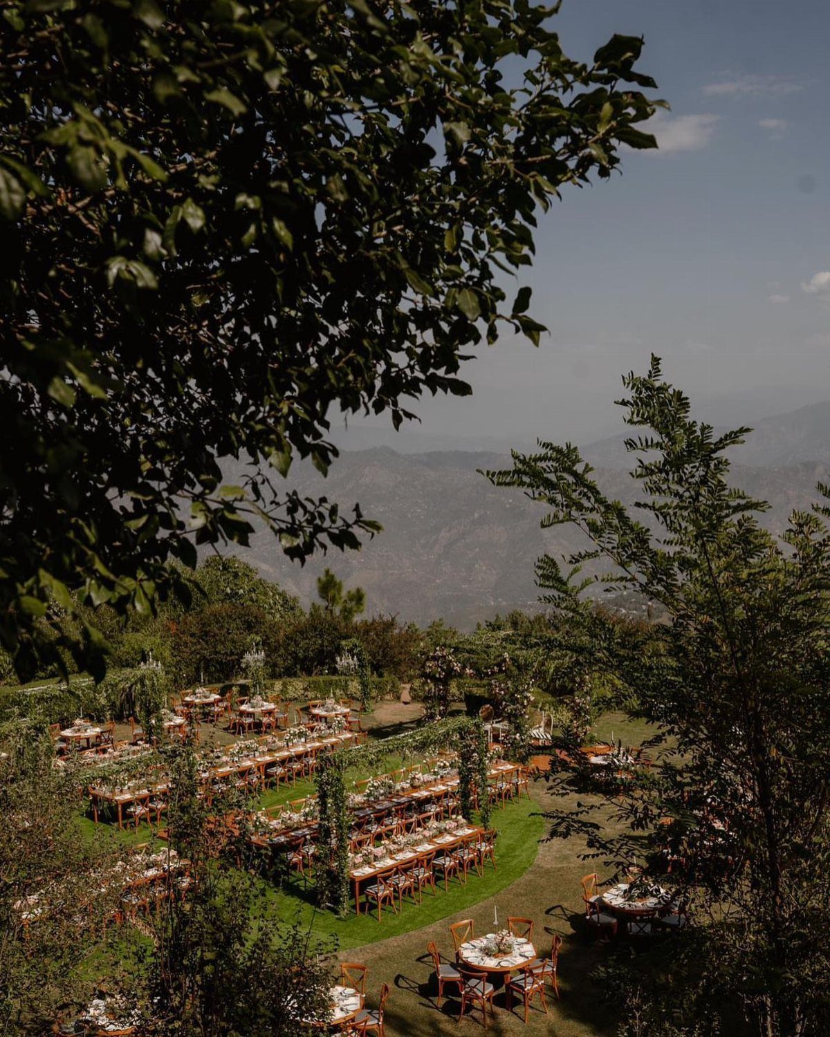 19 Mountain Wedding Ideas for Scenic, Cozy Celebrations 6 Outdoor wedding reception tables set on a grassy hill overlooking distant mountains.