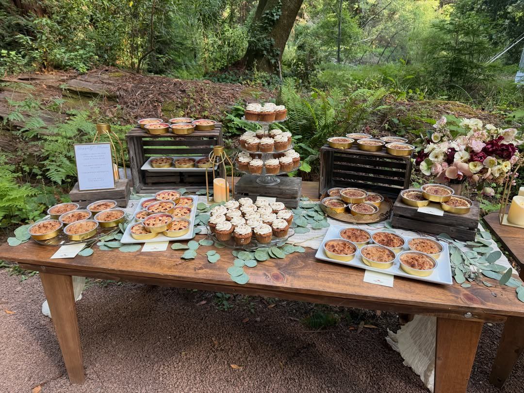 19 Mountain Wedding Ideas for Scenic, Cozy Celebrations 17 Miniature pies displayed on a wooden table with greenery in a forest setting.
