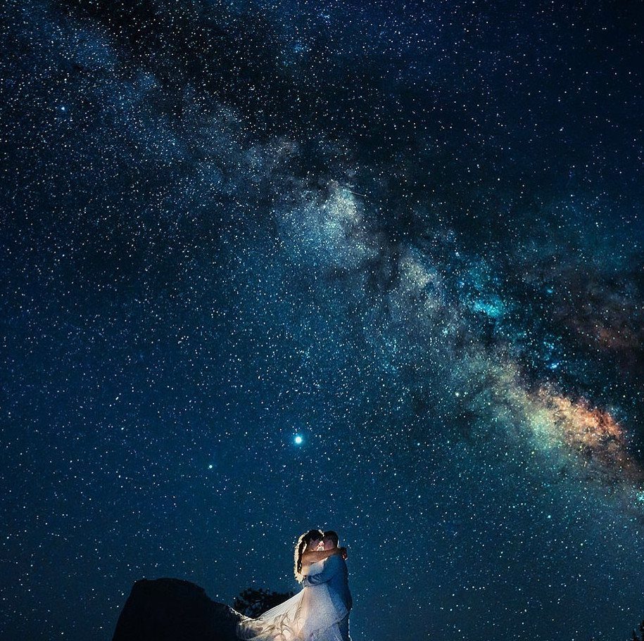 19 Mountain Wedding Ideas for Scenic, Cozy Celebrations 7 Wedding couple embracing on a rock under a brilliant starry Milky Way sky.