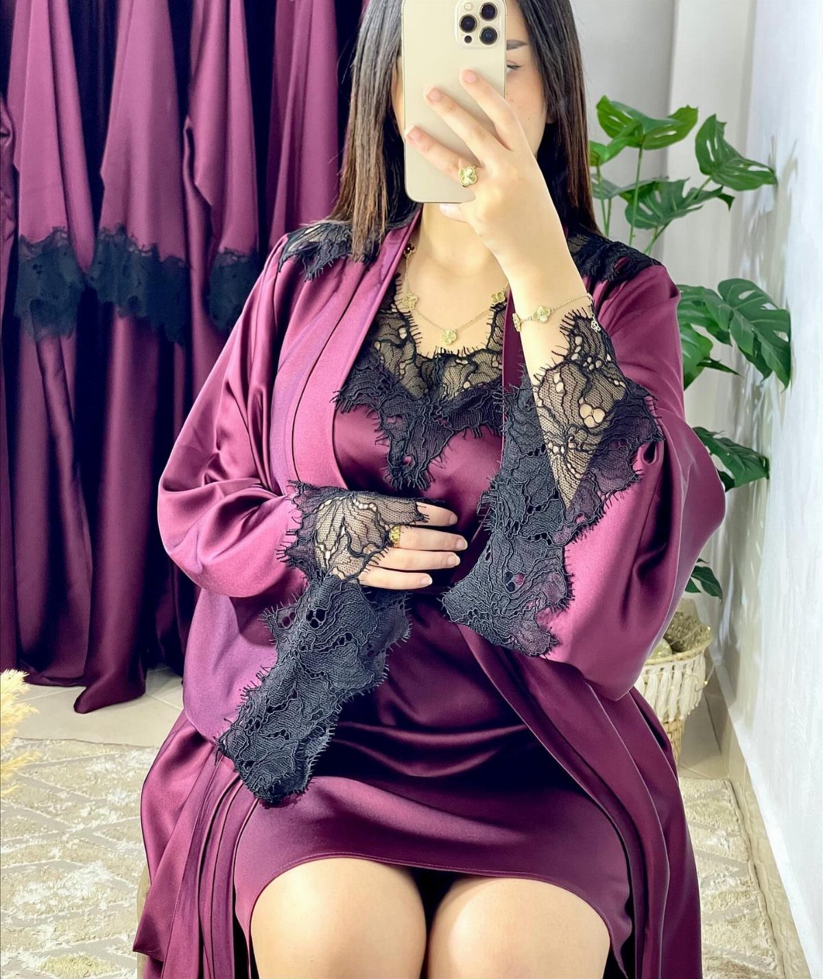 Woman in plum satin nightgown and robe with black lace trim taking a selfie