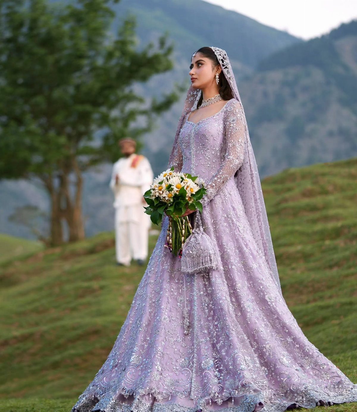 26 Nikah Dress Ideas for Your Perfect Wedding Ceremony 7 Woman in an embellished pastel purple gown and veil holding a white flower bouquet.