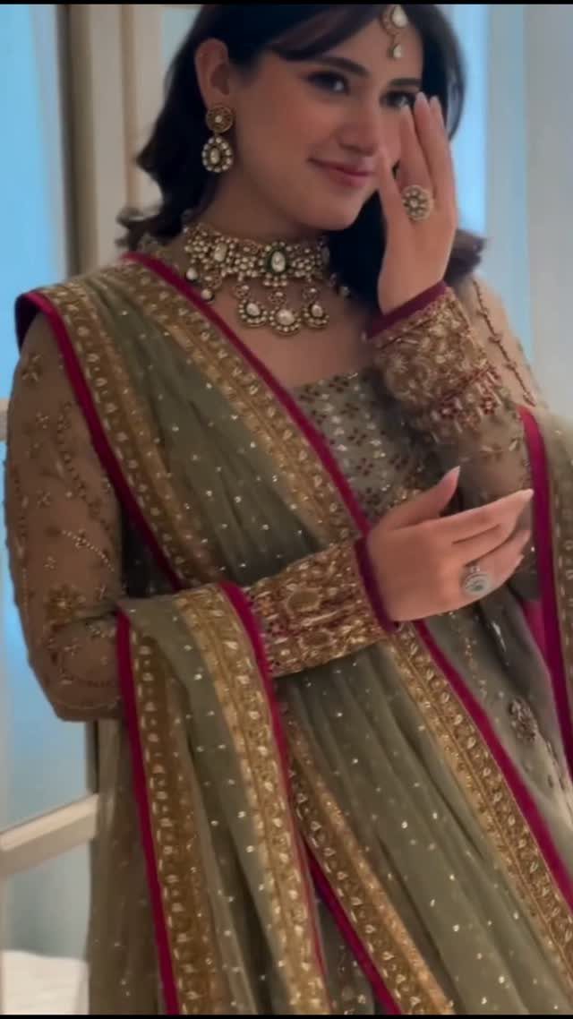 26 Nikah Dress Ideas for Your Perfect Wedding Ceremony 26 Woman in sage green embroidered traditional dress with gold jewelry and red border dupatta.