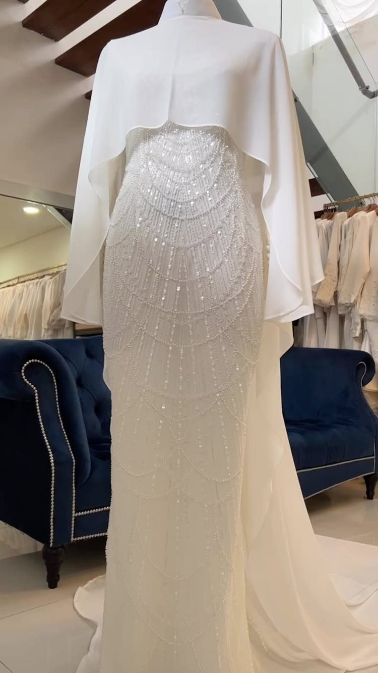 26 Nikah Dress Ideas for Your Perfect Wedding Ceremony 14 White embellished bridal gown with a matching cape on a mannequin in a shop