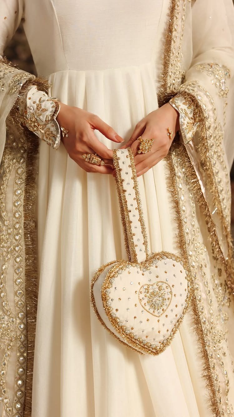 26 Nikah Dress Ideas for Your Perfect Wedding Ceremony 22 White pishwas with gold embroidery and a heart-shaped beaded handbag.