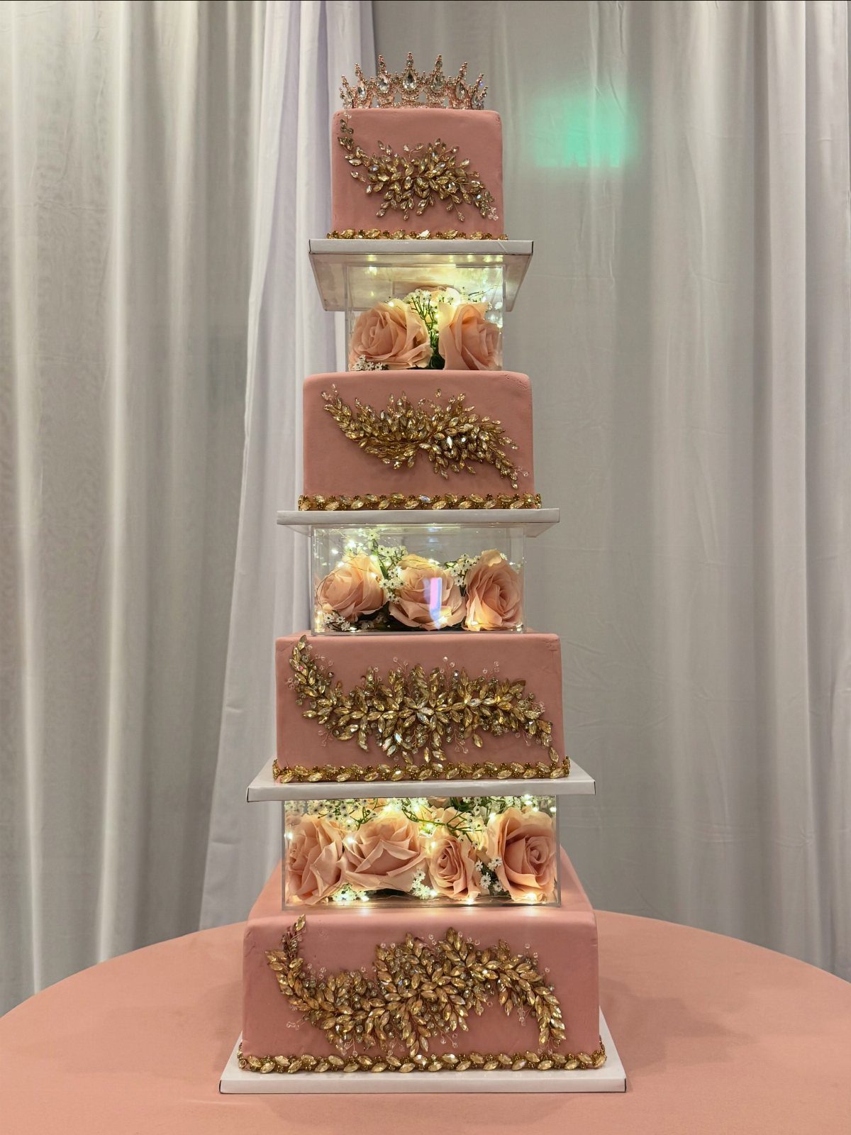 Quince Cake Ideas: 18 Designs From Florals to Butterflies 13 Multi-tiered pink cake with gold accents, tiara topper, and rose-filled clear spacers.