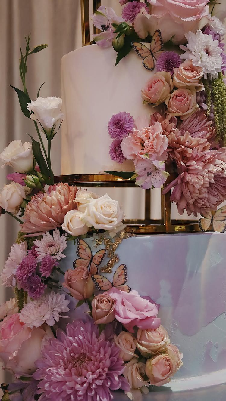 Quince Cake Ideas: 18 Designs From Florals to Butterflies 3 Multi-tiered purple and white cake decorated with pink flowers and small butterflies.