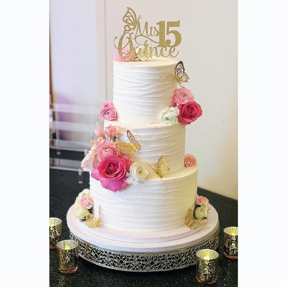Quince Cake Ideas: 18 Designs From Florals to Butterflies 4 Three-tier white round cake with pink roses, gold butterflies, and a gold quinceañera topper.