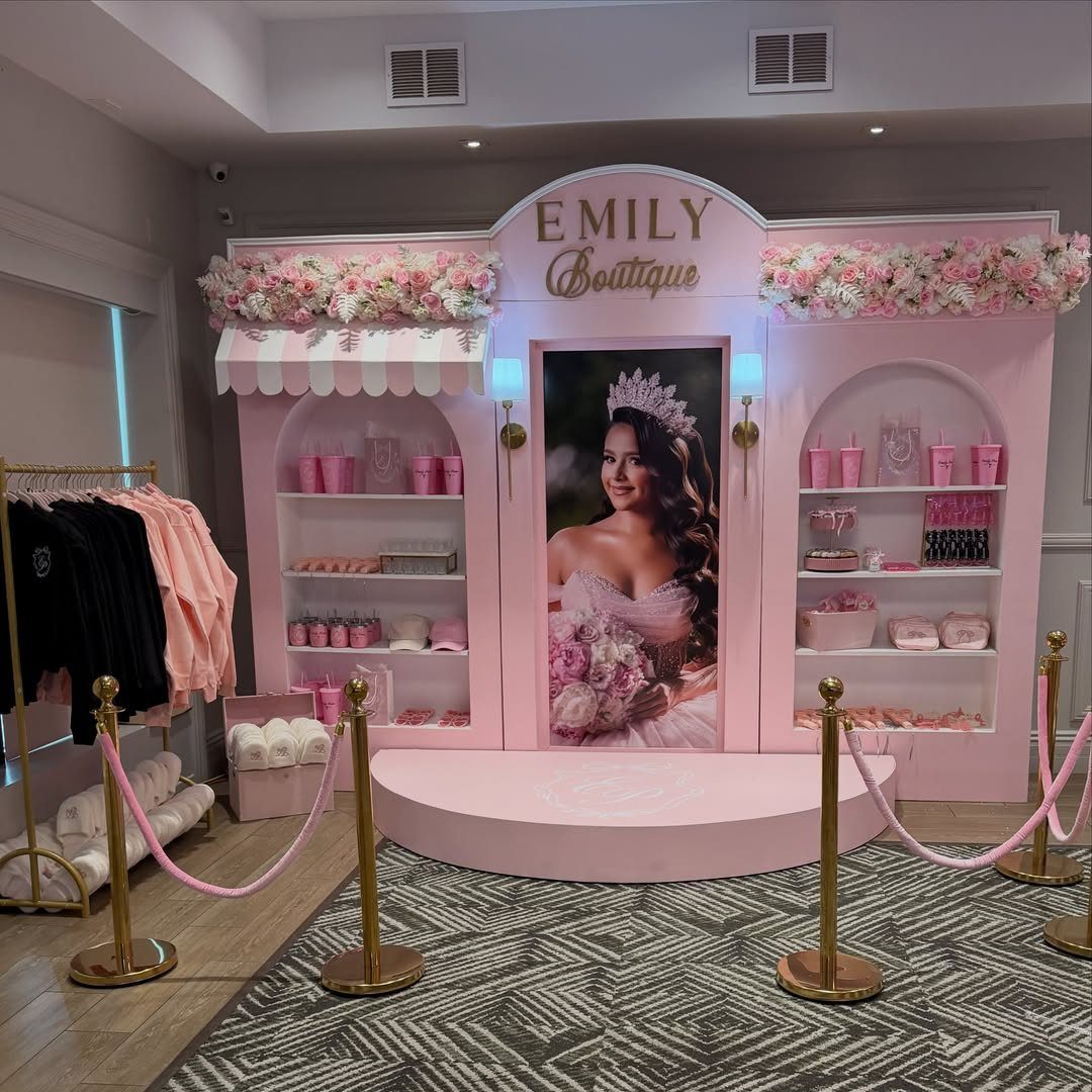 Pink boutique-themed photo backdrop with a large portrait and floral decorations.