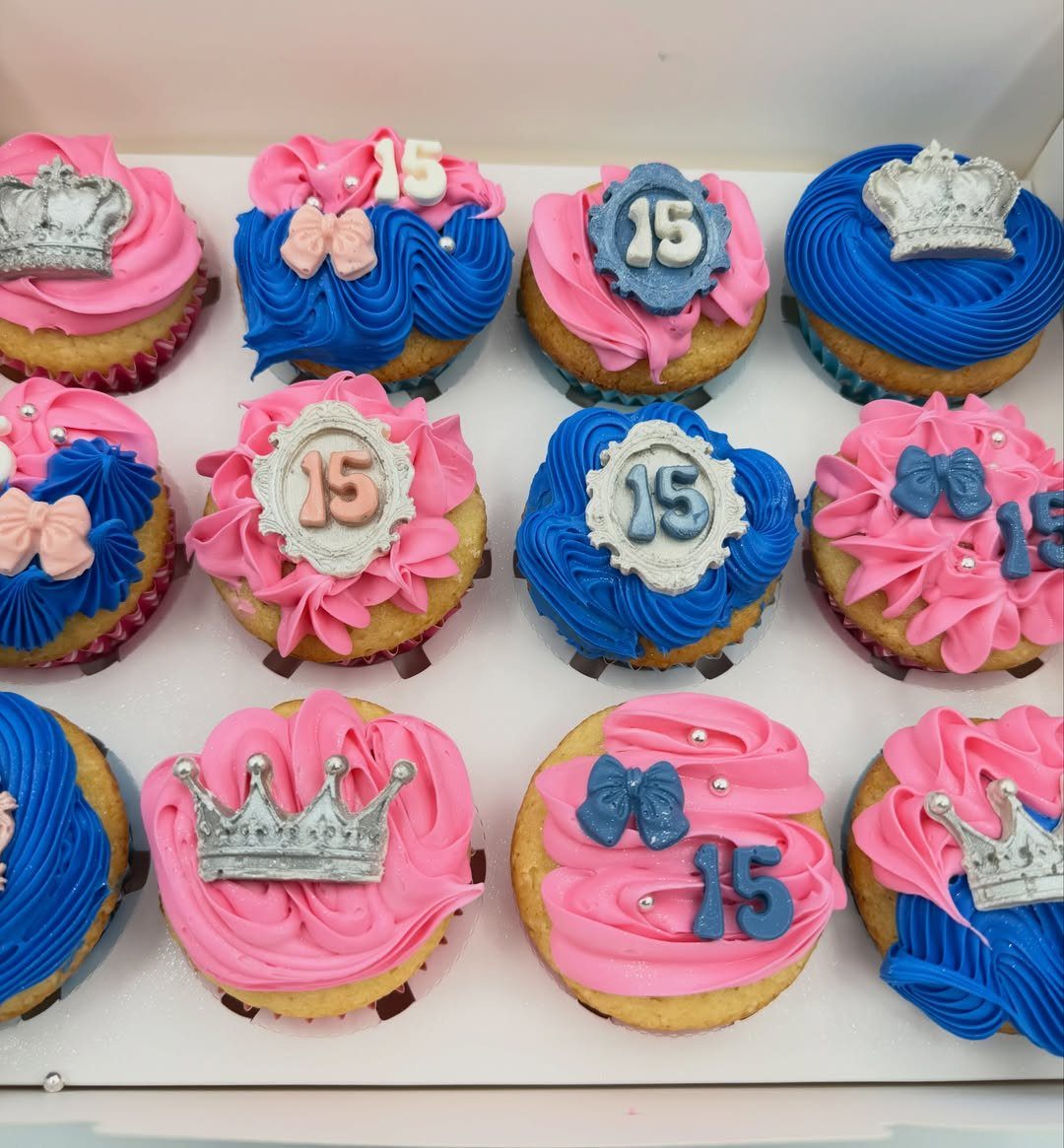 Cupcakes with pink and blue frosting decorated with silver crowns and number 15 plaques.