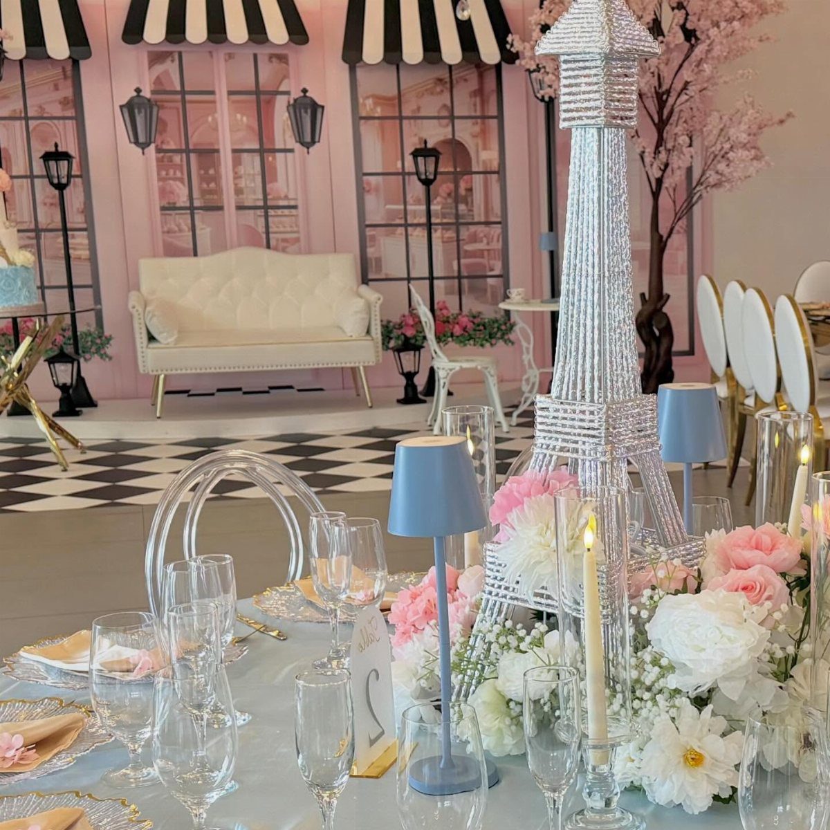 Sparkling silver Eiffel Tower centerpiece with pink and white roses on a decorated table.