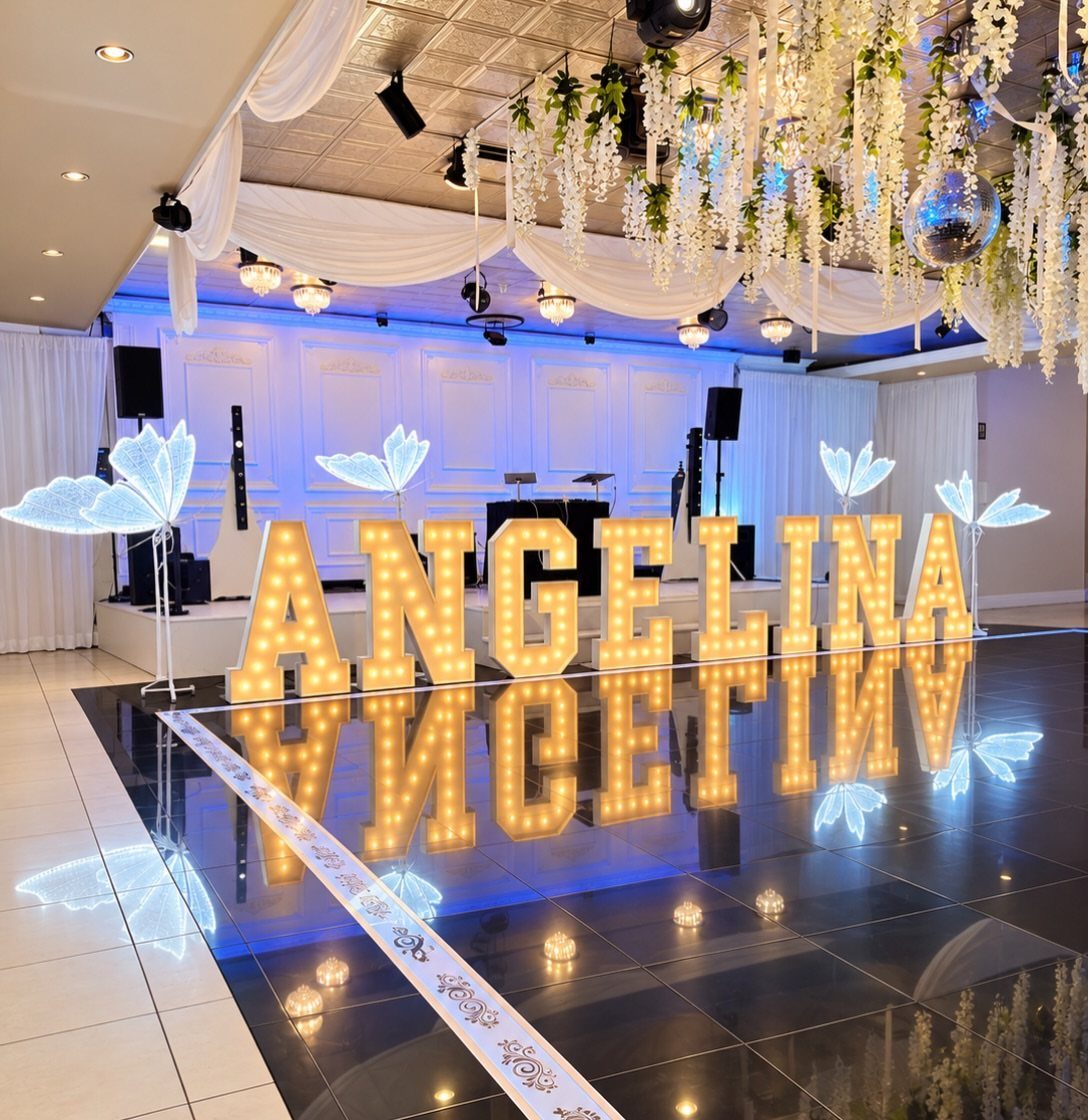 Large illuminated marquee letters spelling ANGELINA on a reflective black dance floor.