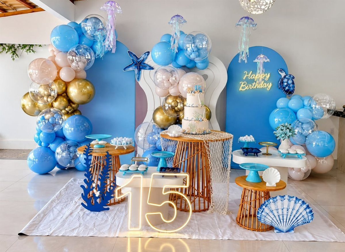 Ocean-themed party decorations with blue balloons, seashell accents, and a glowing number 15.