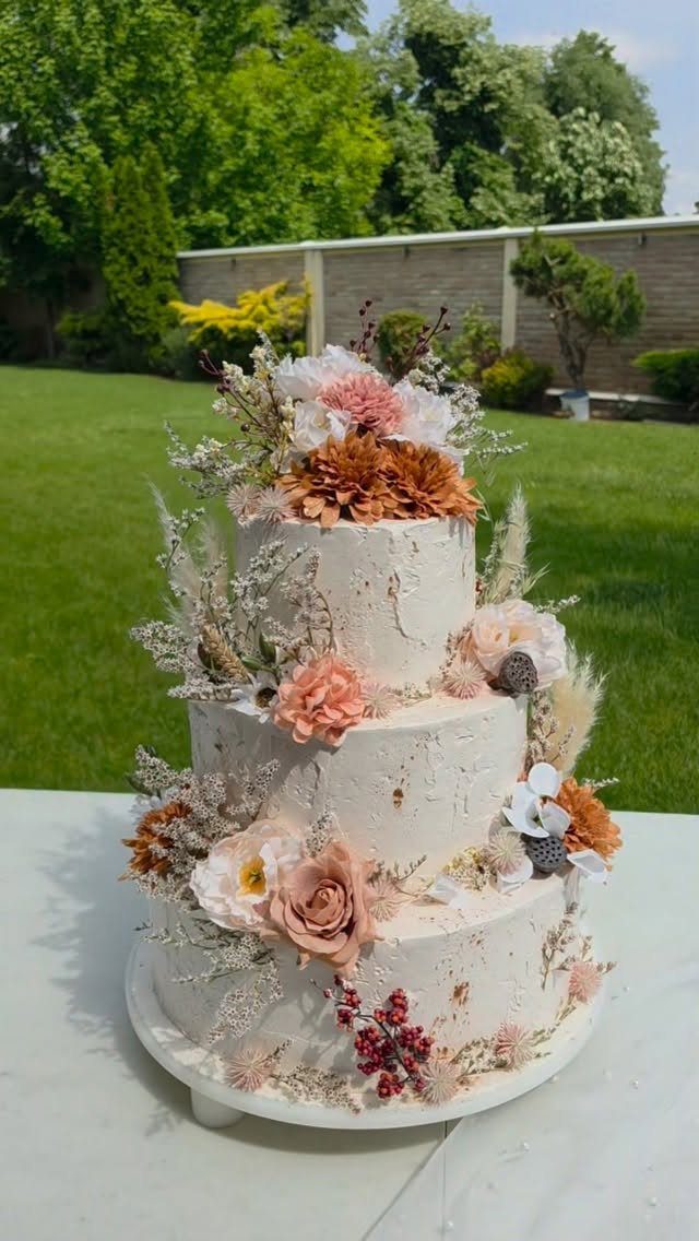 38 Romantic Wedding Cake Ideas for Your Celebration 32 Three-tier white wedding cake decorated with earthy orange flowers and dried pampas grass.