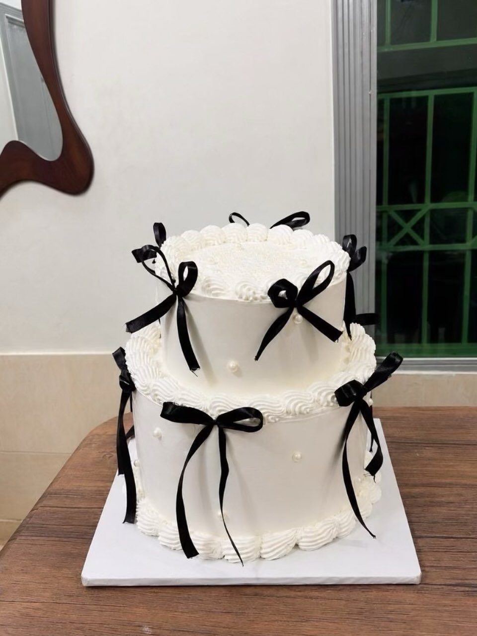 38 Romantic Wedding Cake Ideas for Your Celebration 21 Two-tier white cake decorated with black ribbon bows and small white pearls.