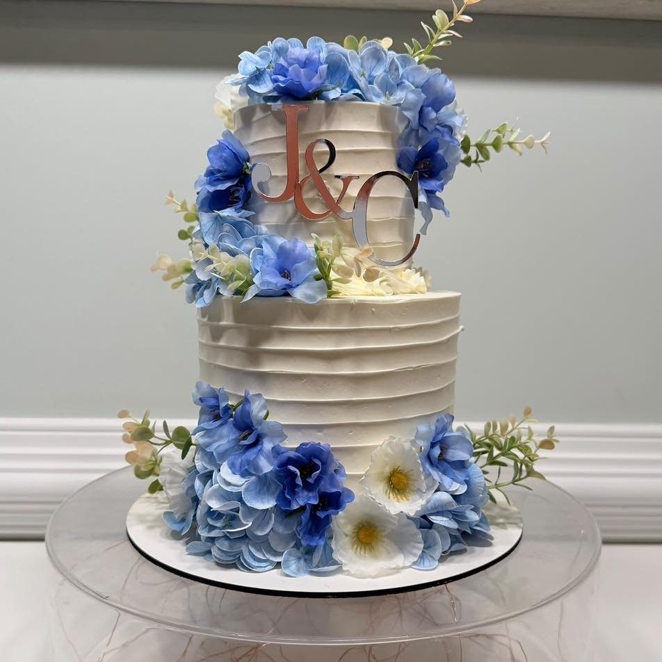 38 Romantic Wedding Cake Ideas for Your Celebration 30 Two-tier white wedding cake decorated with blue and white flowers and silver monogram topper.