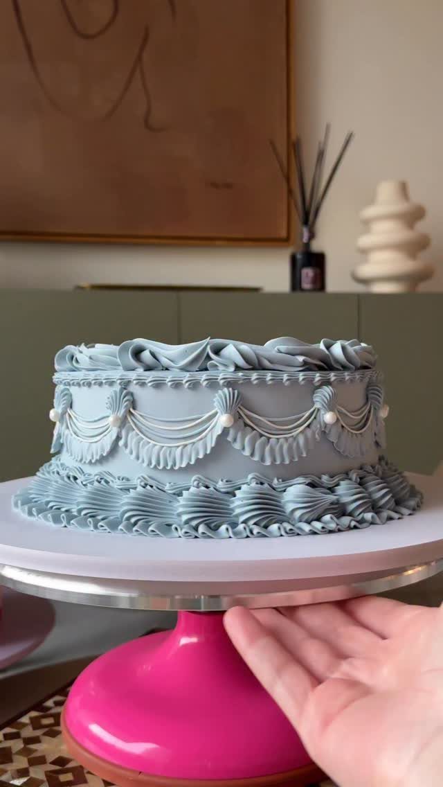 38 Romantic Wedding Cake Ideas for Your Celebration 25 Dusty blue single-tier cake with ornate piping and pearls on a pink stand