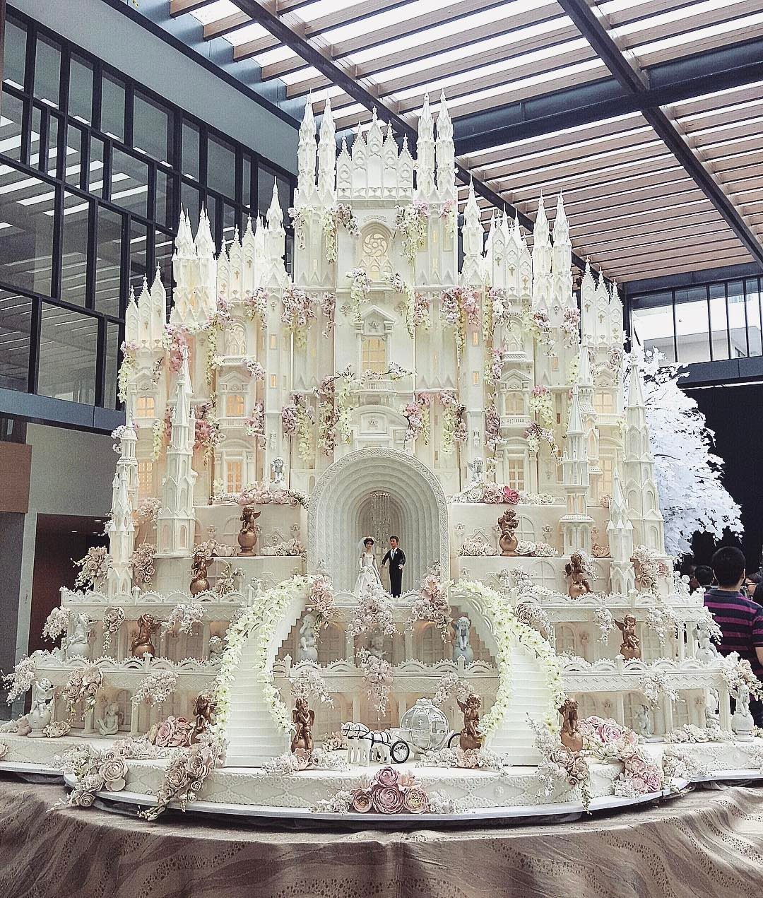 38 Romantic Wedding Cake Ideas for Your Celebration 18 Intricate white castle cake with spires and floral decorations and a tiny couple.