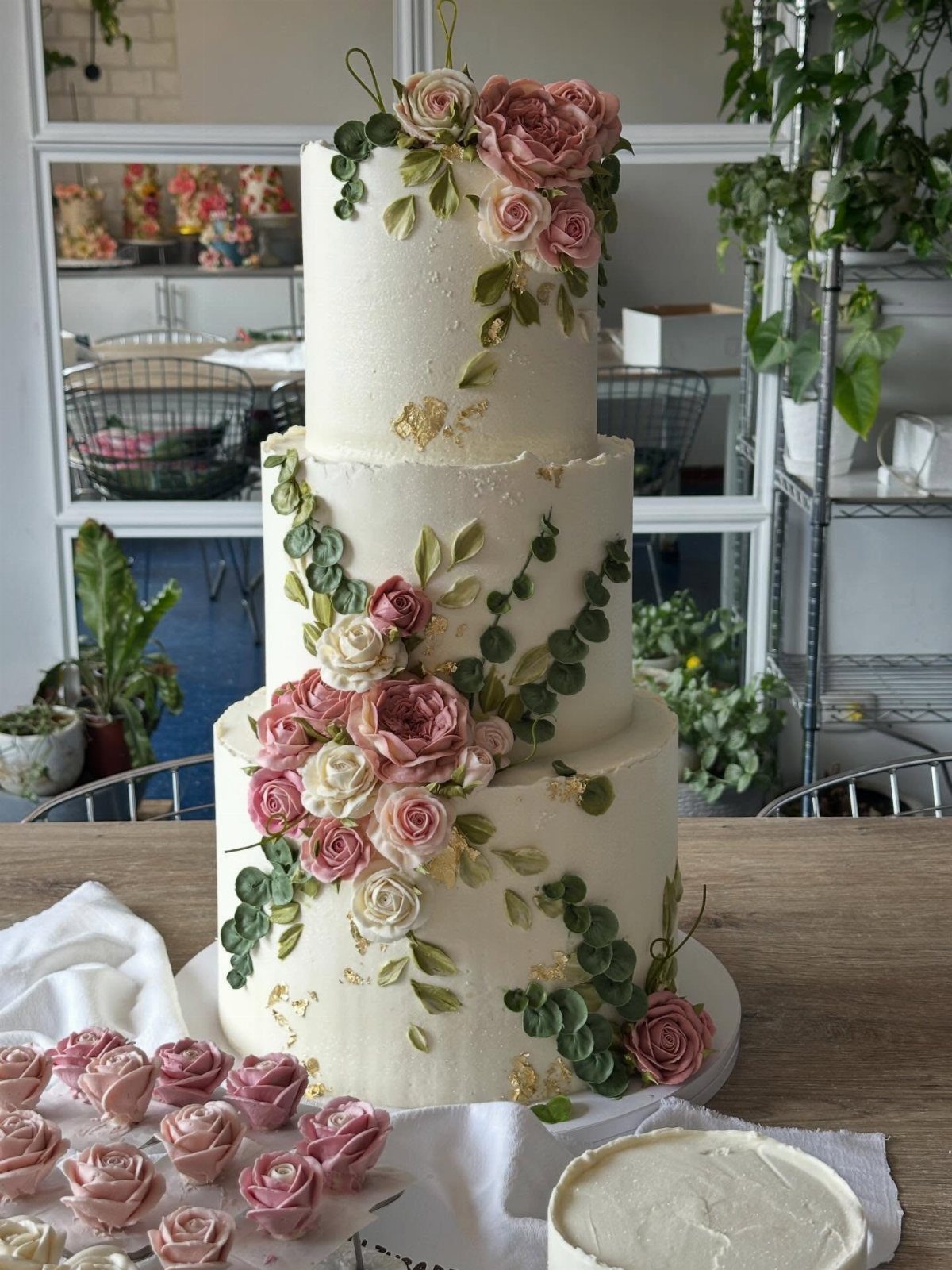 38 Romantic Wedding Cake Ideas for Your Celebration 37 Three-tier white wedding cake adorned with pink and cream buttercream roses and green leaves.